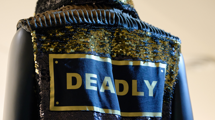 A sequinned garment reading 'DEADLY' in bold gold text