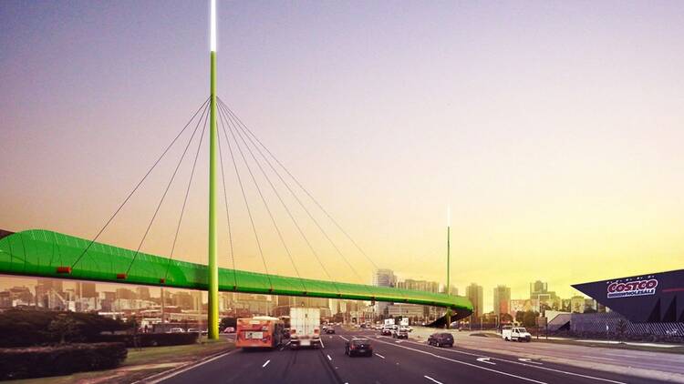 A green cycling bridge suspended over traffic in Melbourne.