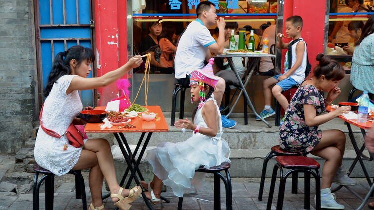 Families eat noodles outside a restaurant in China's capital city. 