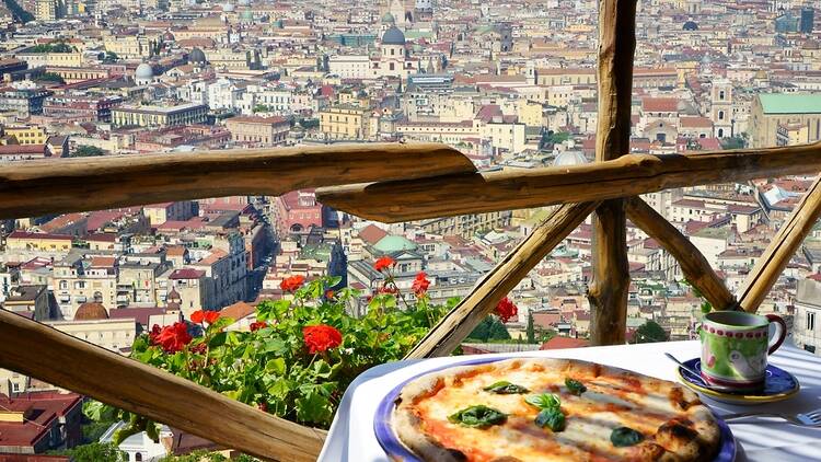 Pizza in foreground with view of Naples in background