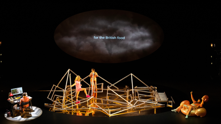 Actors navigate a scaffold with the words 'for the British food' projected above them'