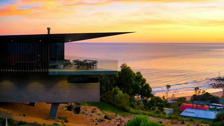 A house overlooking the ocean at sunset. 