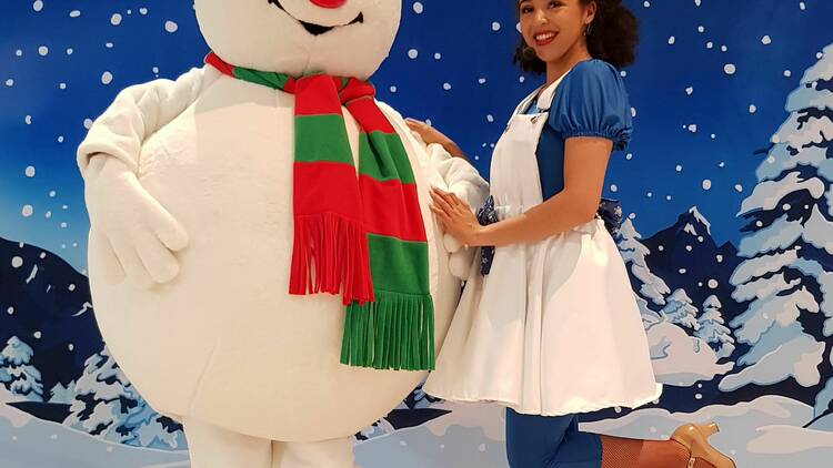 A person posing with a life-size snowman character. 