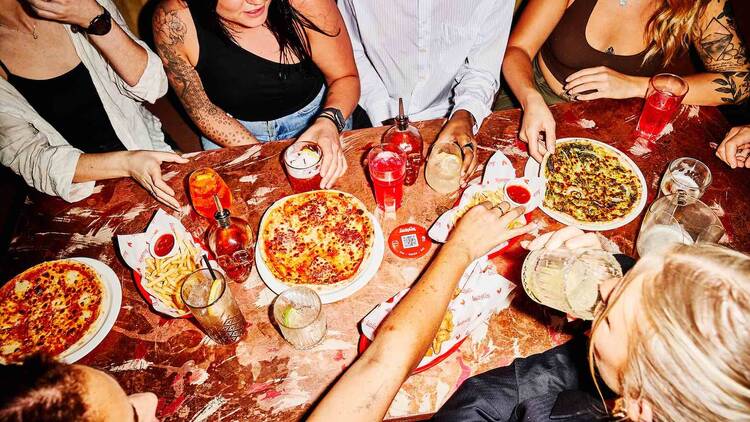 Group of friends sharing pizzas.