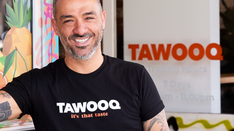 Tawooq staff smiling in front of store.