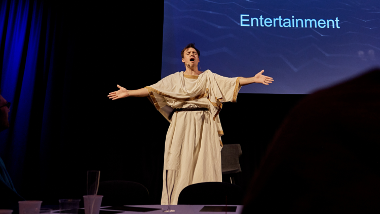 Performer exclaims in front of a projection of the word entertainment