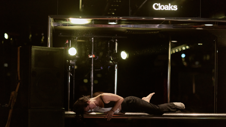 A performer lies on the cloakroom counter at the Arts Centre