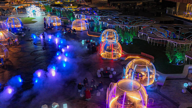 Igloos on a rooftop with lots of neon lights
