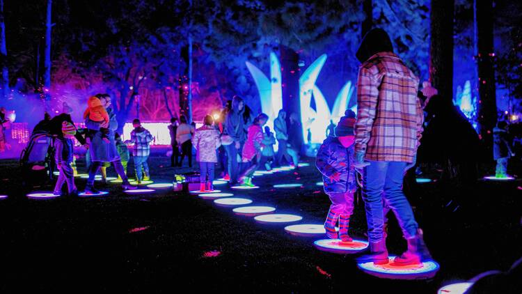 People walking along illuminated stepping stones. 