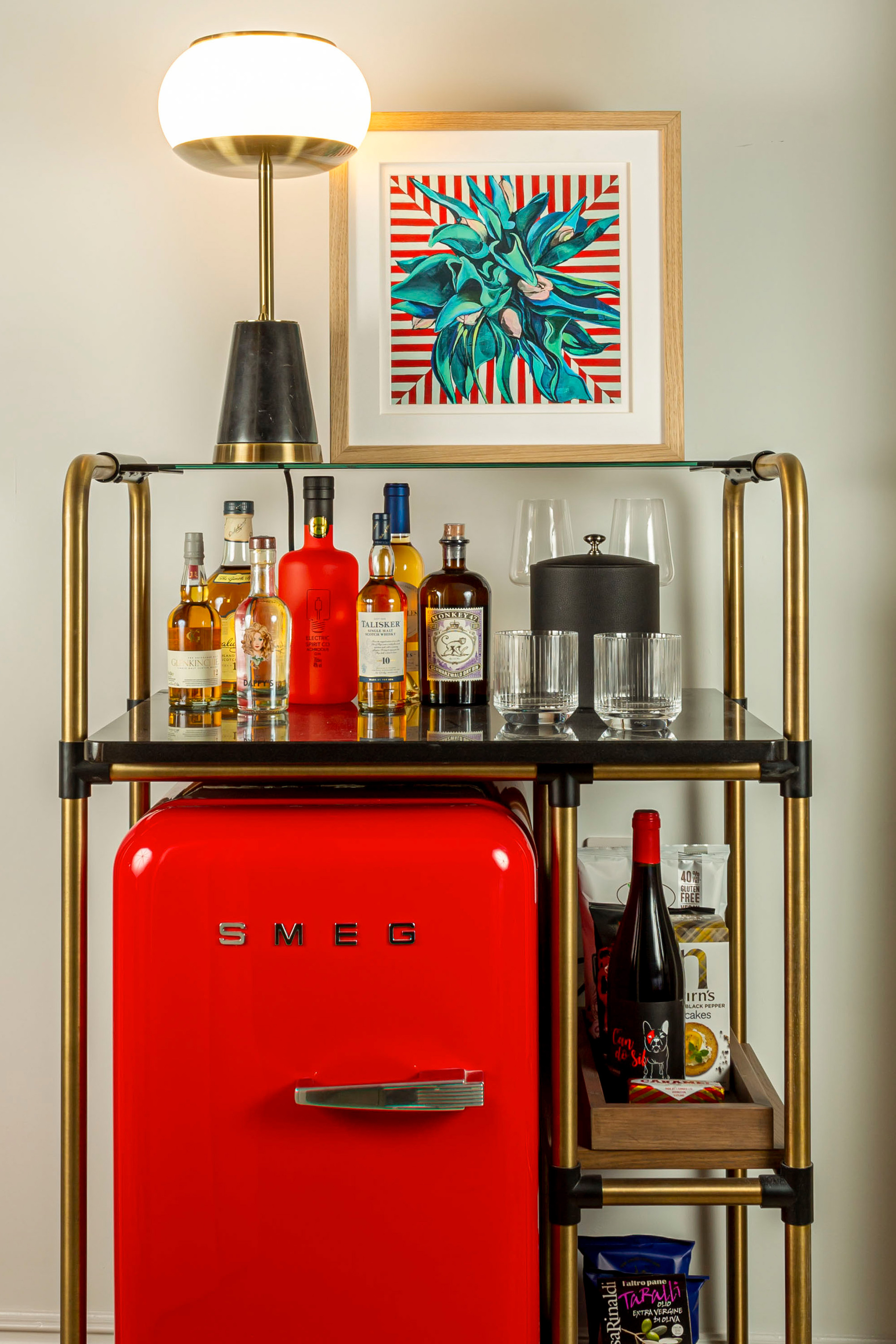 Red fridge surrounded by bottles and glasses