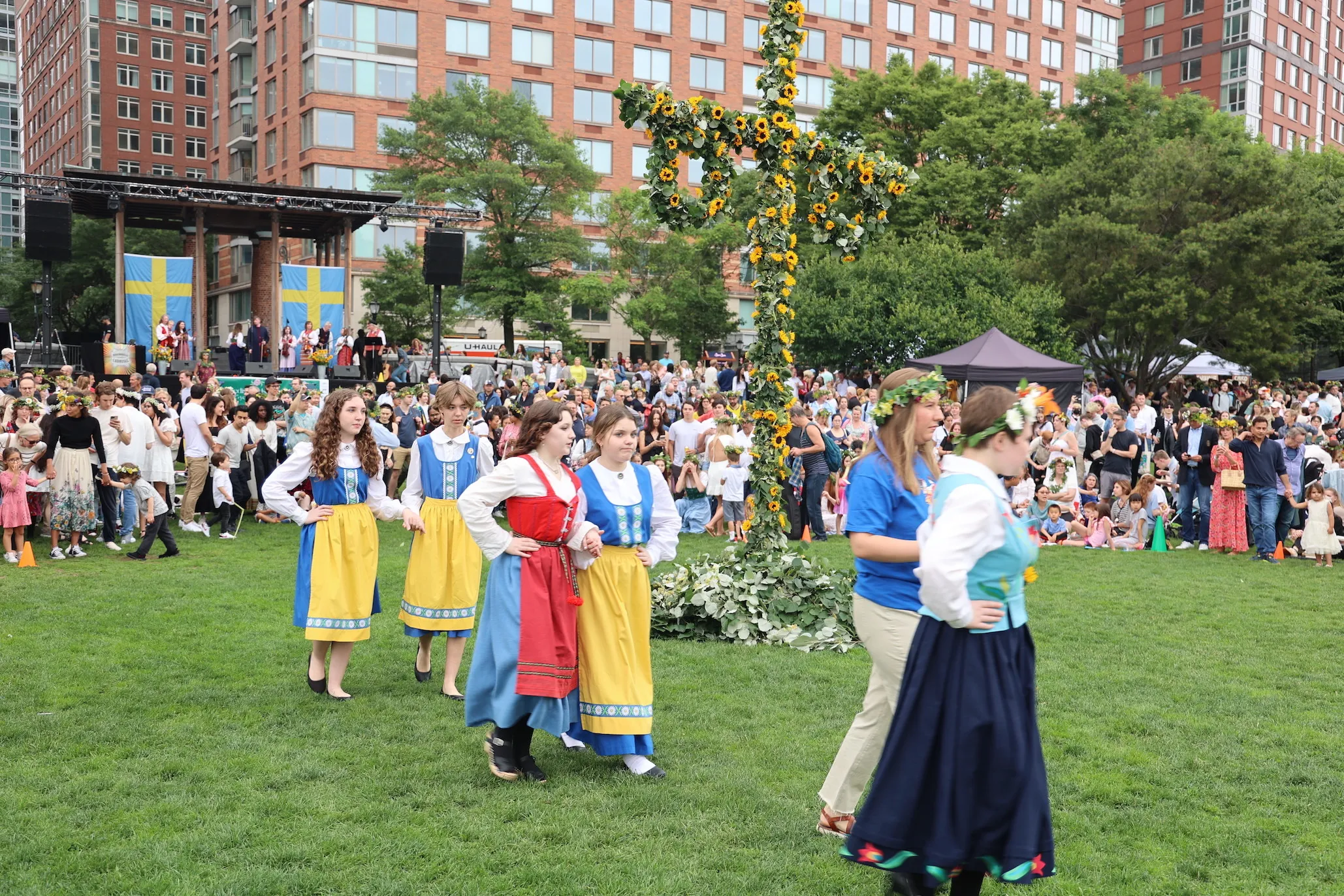 People in traditional Scandinavian dress walk by a Maypole.