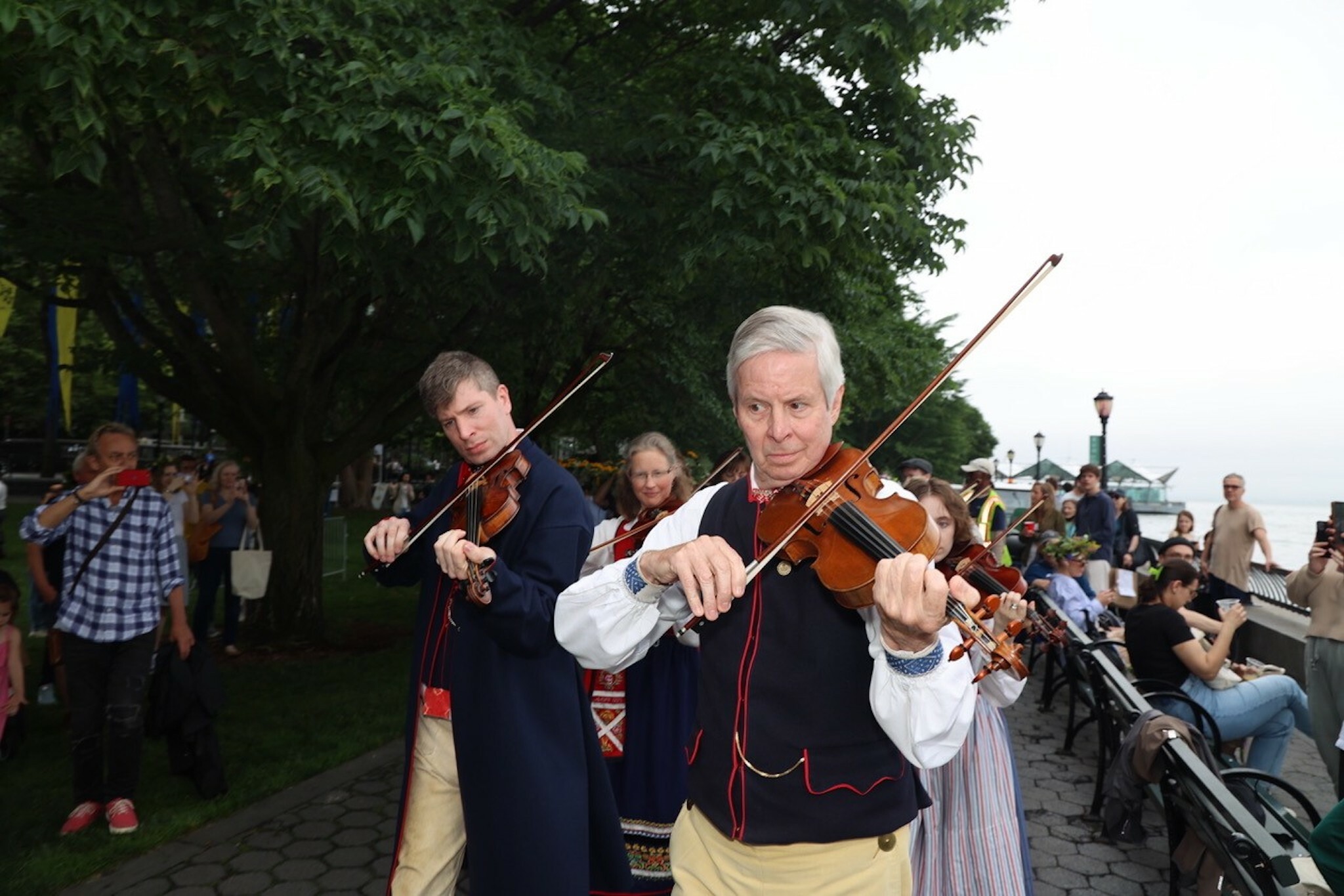 Men play fiddles at the Swedish Midsummer Festival.