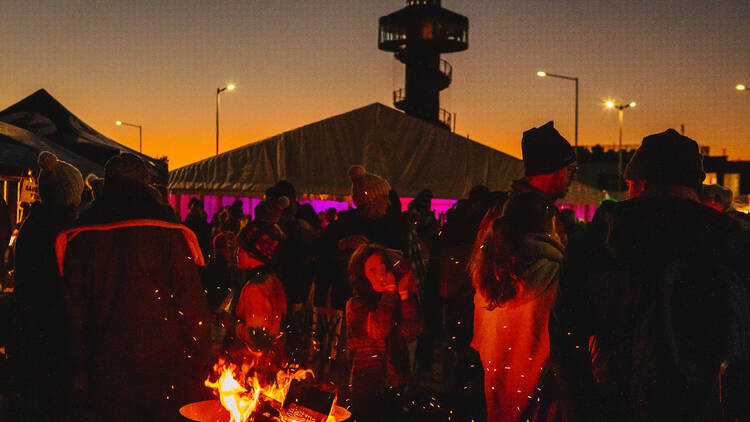 People gathering around a bonfire at sunset.