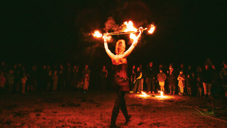 A performer holding a hoop alight with fire. 