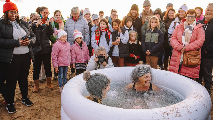 Two people in an ice bath on the beach. 