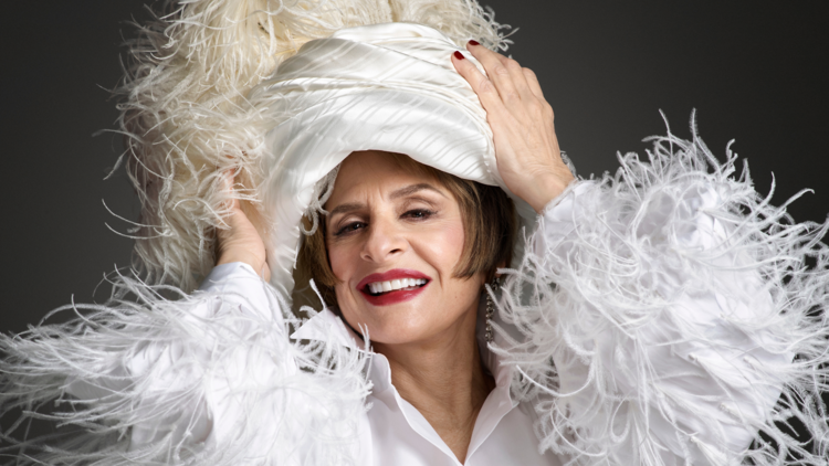 Patti LuPone wears white turban and outfit covered in white feathers