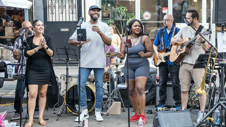 A band performs on a sidewalk.