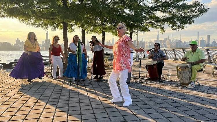 Women dance along the river.