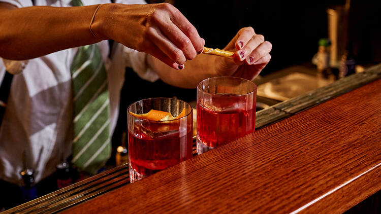 A bartender making two Negronis.