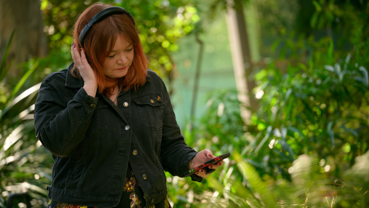 A person listens to audio in headphones in the forest gallery at Melbourne Museum