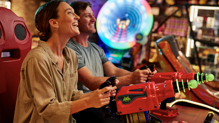 Two people playing a shooter game at a arcade