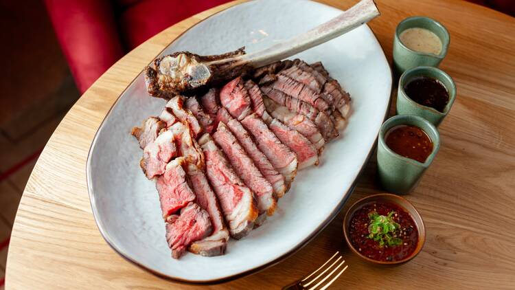 A plate of sliced steak, with sauces on the side