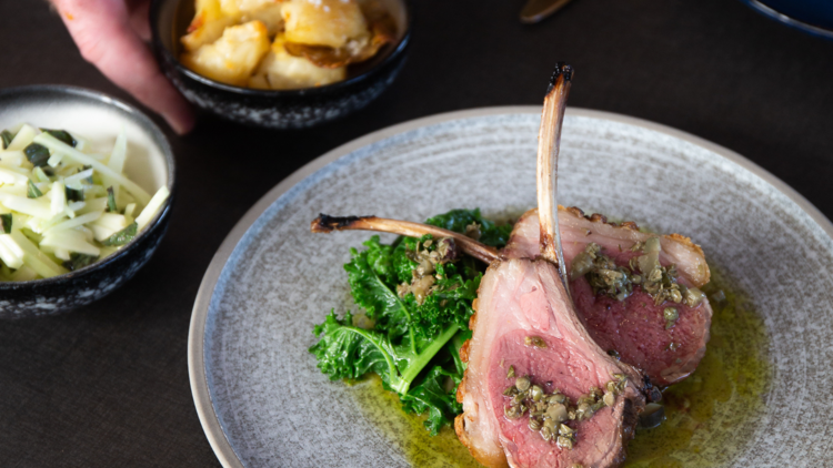 Lamb chops presented on grey plate with kale