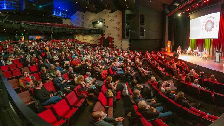 A crowd of people in a theatre watching a live talk