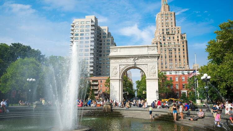 People gather at the fountain in Washington Square Park on a sunny summer afternoon.