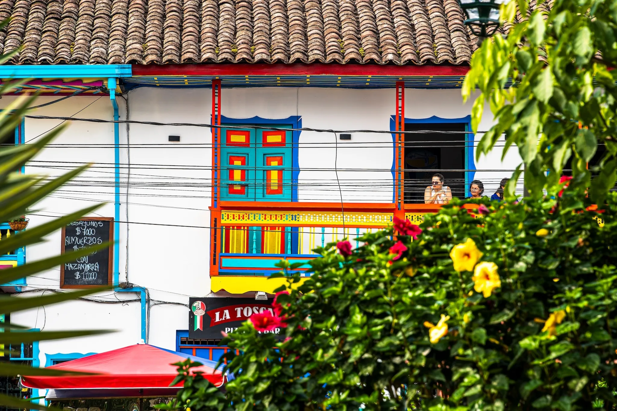 People stand on a balcony attached to colourful house in Filandia, Quindio, Colombia