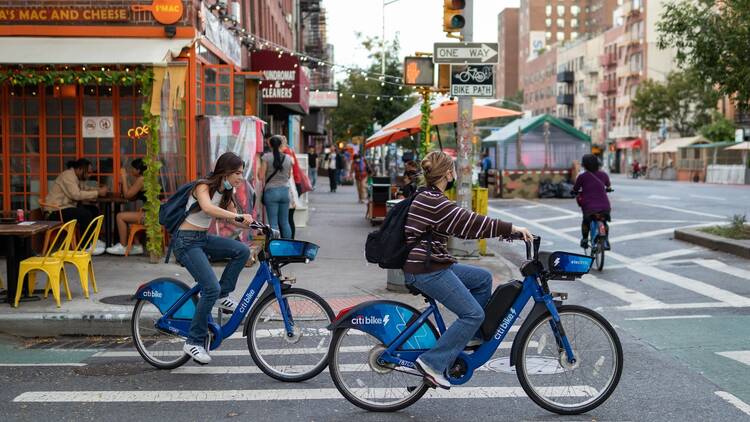 Two people Riding Citi Bikes on a Street in the East Village of New York City