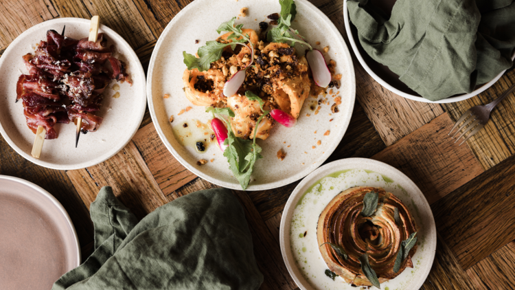 Spread of food dishes on wood table with green napkin