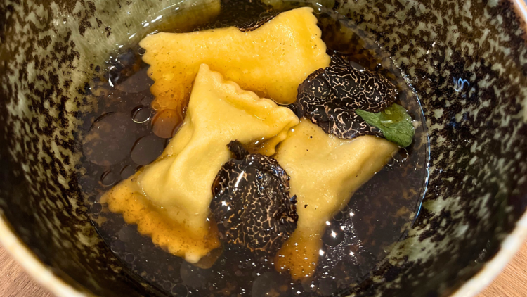 3 pieces of agnoloti pasta in soup with truffle shavings