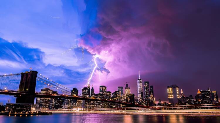 Lightning strike through New York City from Brooklyn bridge perspective. 