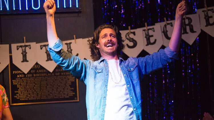 A performer standing on the stage with hands in the air 