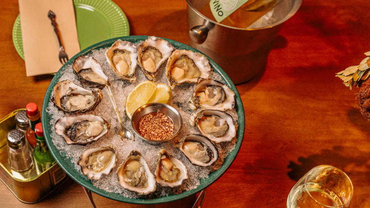 Platter of oysters, bottle of wine in an ice bucket and a glass of white wine.