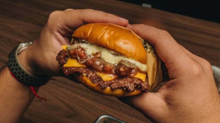 A smashburger from Cowy Burger held in someone's hands