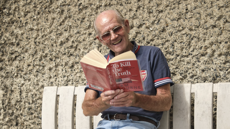 Image of man reading To Kill the Truth on a bench