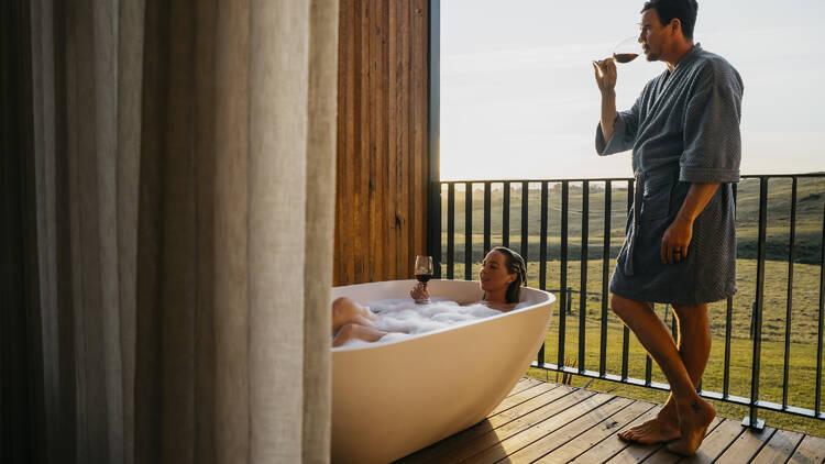 A couple using the outside bathtub at Cupitt's Estate