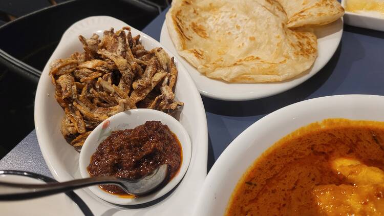 fried anchovies with chilli sauce next to a plate of roti