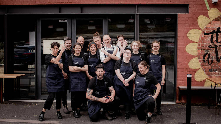 Group of waitresses and waiters smiling outside cafe