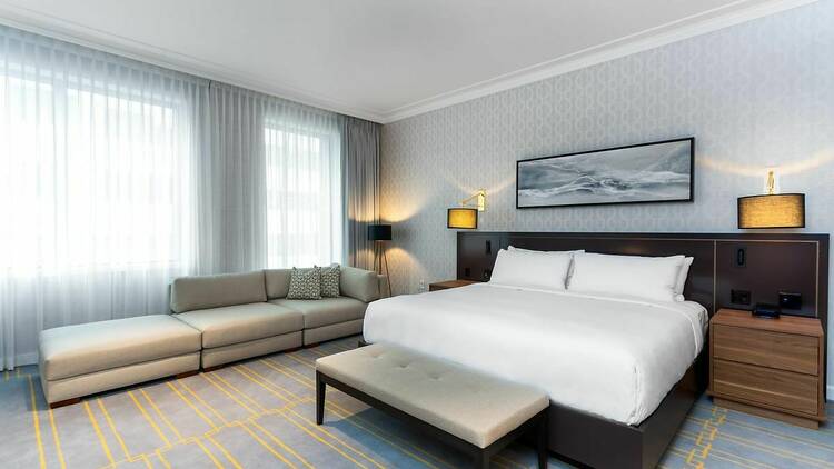 A hotel room with a gray design and white bed.