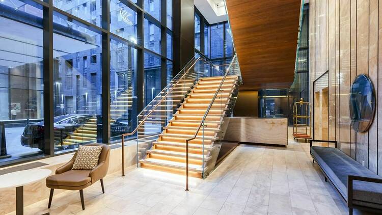 The lobby of a hotel with a lighted staircase.