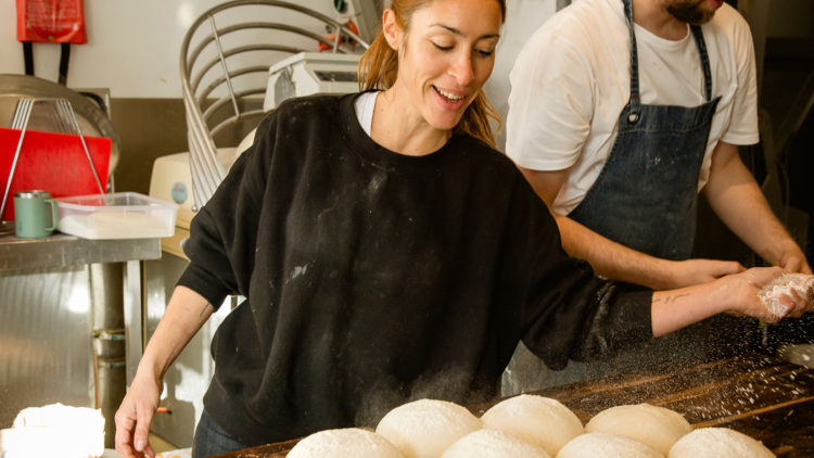 Baker sprinkling flour on bread