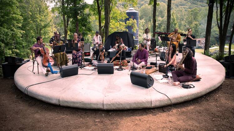 "In D" performing on a circle stage in the woods. 