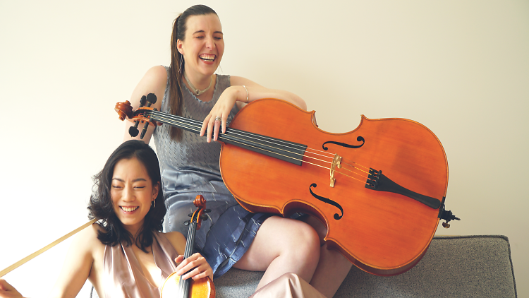 Laura Zawarski and Violet Wang holding a cello and violin