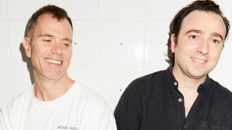 Both members of the Presets smile against a white tile backdrop