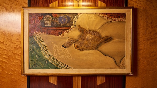 A painting on a sleeping cow tucked in a bed that hangs in the interior of Le Veau d'Or