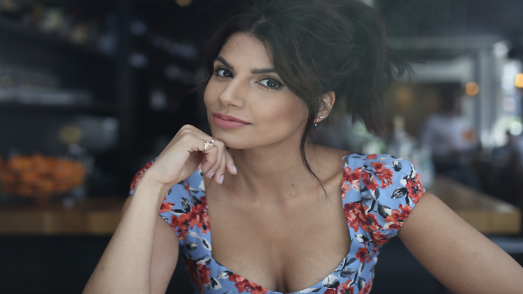 Image of Ruby Bhogal sitting at table smiling 