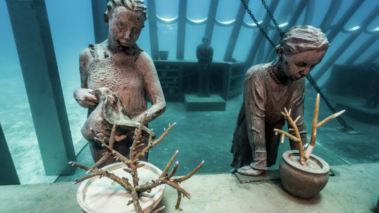 Underwater sculpture figures with coral plants